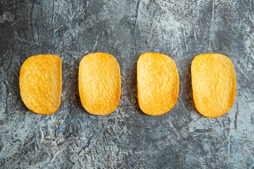 Preview: Horizontal view of crunchy baked chips lined up in a row on gray background