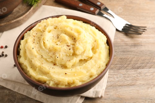 Preview: Bowl of tasty mashed potatoes with black pepper served on wooden table
