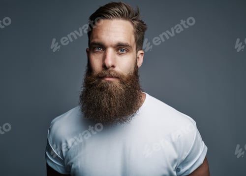 Preview: Bearded young man standing confidently against a gray background