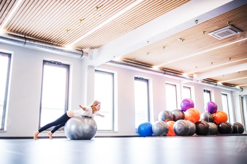 Preview: Young woman doing exercise with a fitball in a gym.