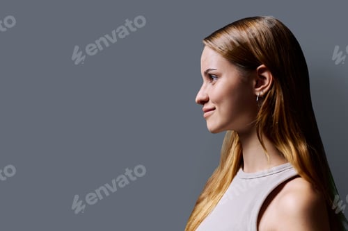 Preview: Headshot portrait in profile beautiful smiling young woman with red hair on gray background