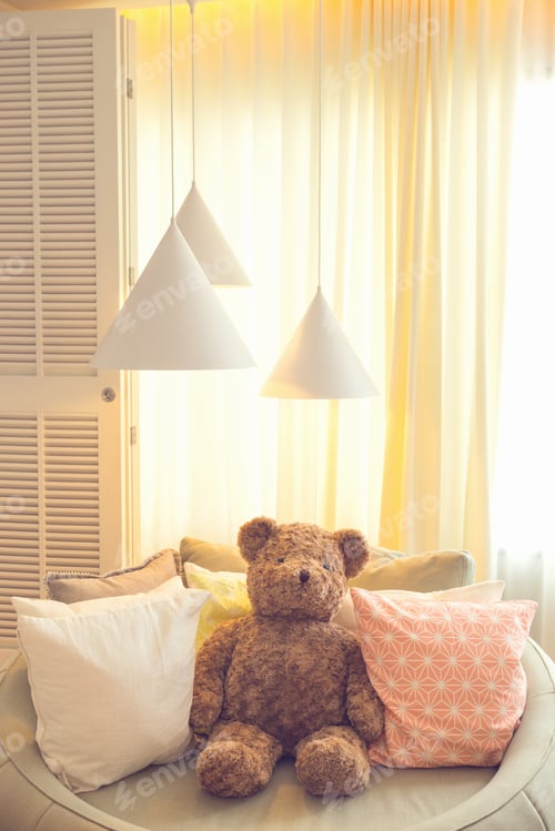 Preview: teddy bear doll sit on sofa with pillow and lamp against curtain and large window in kid bedroom