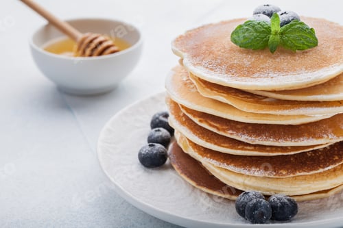 Preview: A stack of delicious pancakes with honey and blueberries on a light blue background