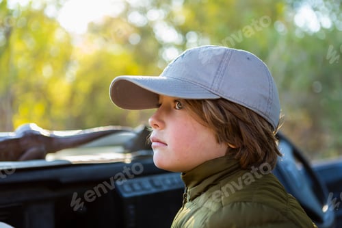Preview: Portrait of young boy in a baseball cap in a safari vehicle.