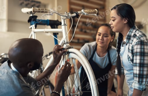 Preview: Shot of three colleagues working together to fix a bike at a bicycle store