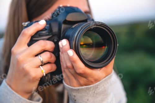 Preview: A young woman with a professional camera takes a photo in nature.