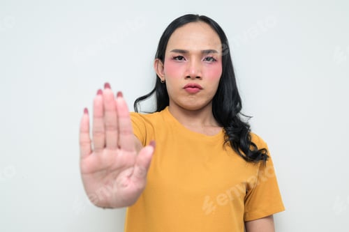 Preview: Portrait of a young Thai transgender person against white background making STOP hand gesture
