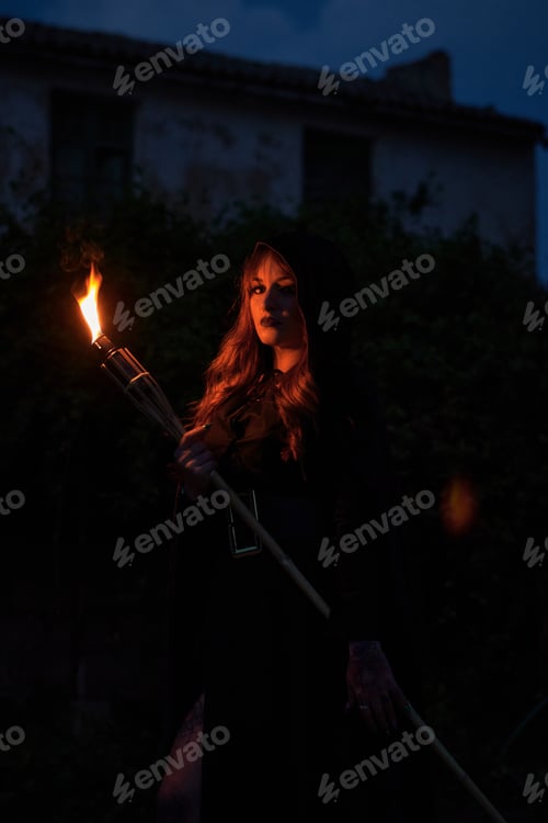 Preview: Woman disguised as a witch holding a flaming torch