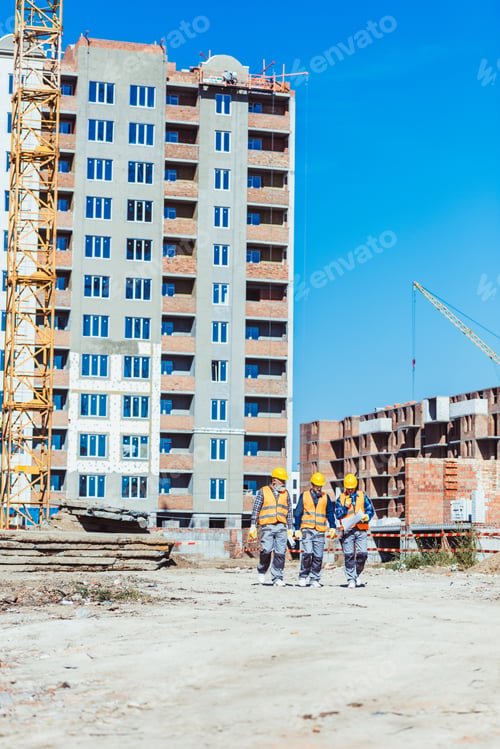 Preview: Three builders in hardhats and vests walking towards camera at construction site