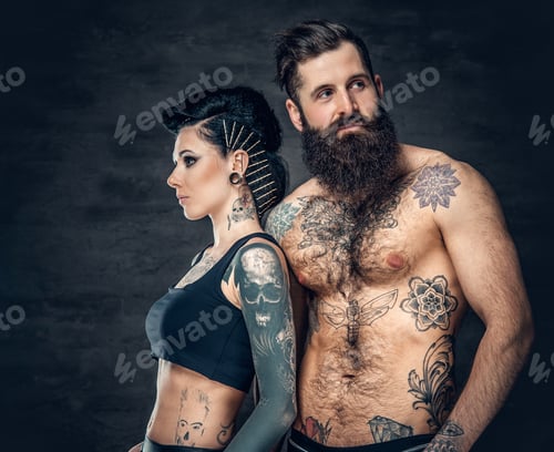 Preview: Studio portrait of full body tattooed couple over dark grey background.