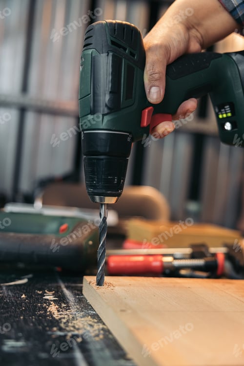 Preview: Hands drilling a hole with the drill on a piece of wood