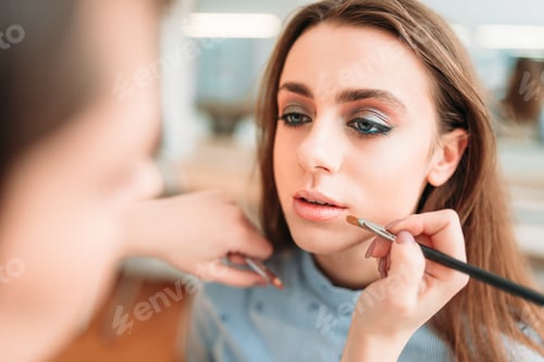 Preview: Make up artist hand applying gloss on woman lips