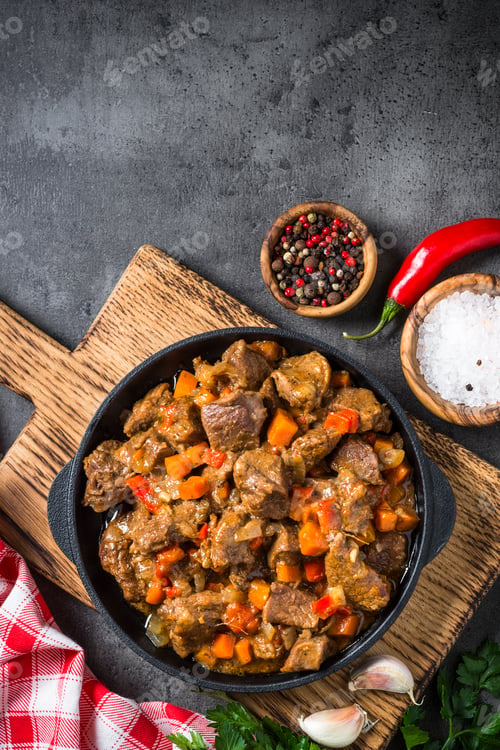 Preview: Beef stew with vegetables in iron pan on black.