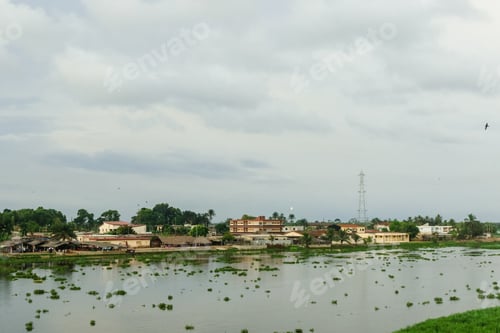 Preview: Picturesque view of Grand Bassam with lush greenery and river under a cloudy sky