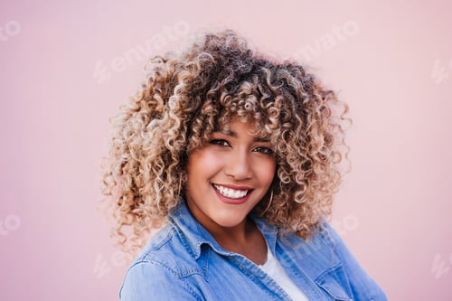 Preview: portrait of smiling hispanic woman with afro hair in city during spring. Urban lifestyle