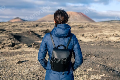 Preview: Back view of traveler woman enjoy unique volcanic landscapes of Lanzarote