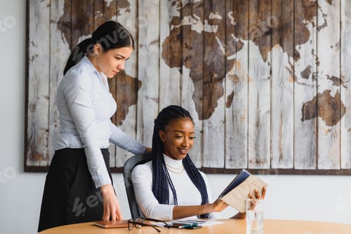 Preview: Two attractive young women at work in an office having a discussion as they share a laptop