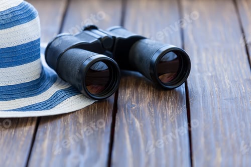 Preview: Binoculars and Striped Hat on Wooden Surface