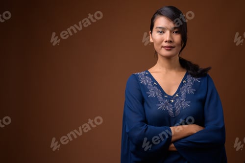 Preview: Studio shot of beautiful Asian woman against brown background
