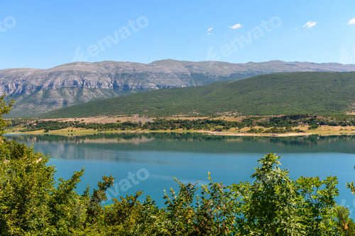 Preview: Lake Peruca in Croatia surrounded by trees, hills and Dinara mountain range on a sunny day