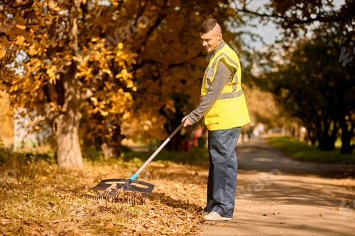 Preview: A man in a yellow vest with rake in the park