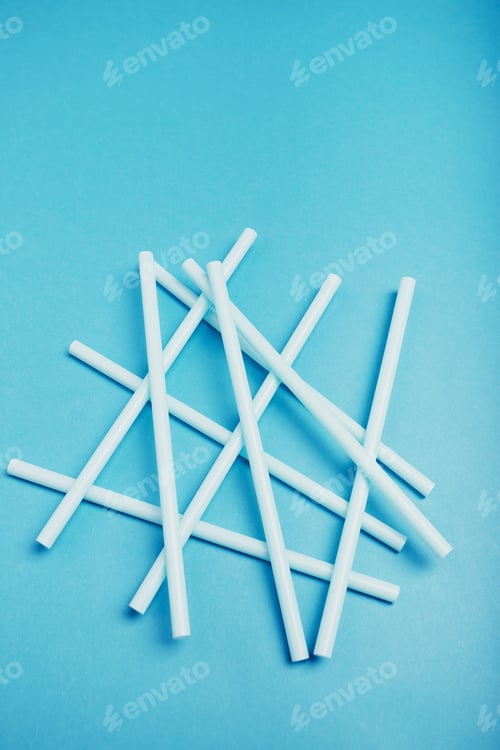 Preview: Heap of plastic straws scattered over blue background