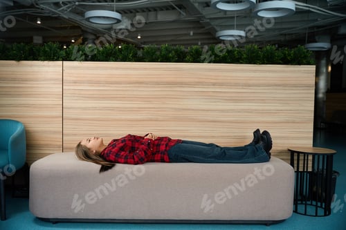 Preview: Side view of young thoughtful asian female employee lying on sofa and looking up