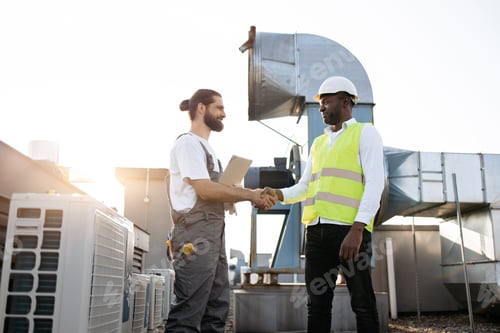 Preview: Multicultural workers smiling and shaking hands on roof