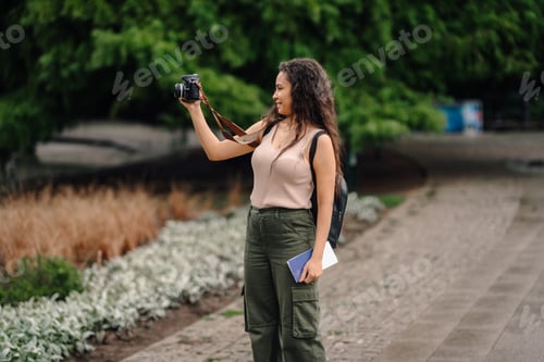 Preview: Young tourist taking photos in a park with retro camera