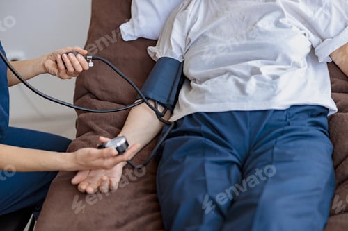Preview: Close up of nurse checking blood pressure of woman in the ward of modern clinic
