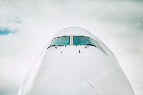 Preview: Front view of the airplane nose against cloud sky.