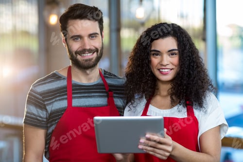 Preview: Portrait Of Smiling Waiter And Waitress Using Digital Tablet At Counter In Cafe