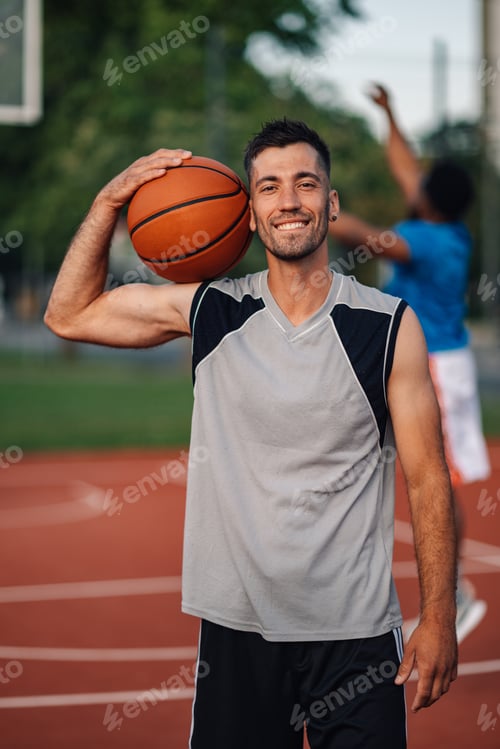 Preview: Smiling player with basketball outdoors