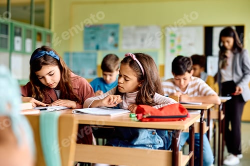 Preview: Hispanic schoolgirl learning while attending a class in the classroom.