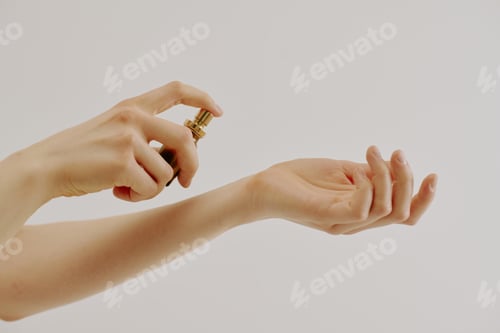 Preview: Woman Sprays Fragrance on Wrist Against White Background