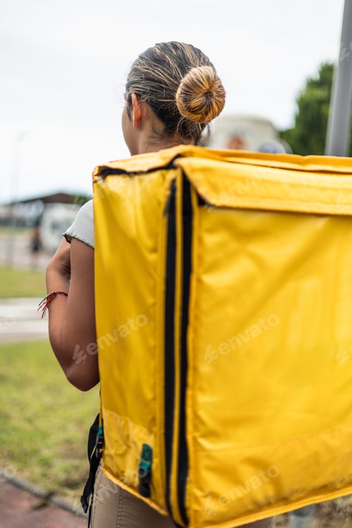 Preview: vertical closeup Hispanic food delivery girl with yellow backpack walking