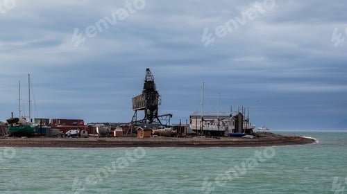 Preview: A historic tower stands alongside abandoned buildings near the water in Longyearbyen Svalbard