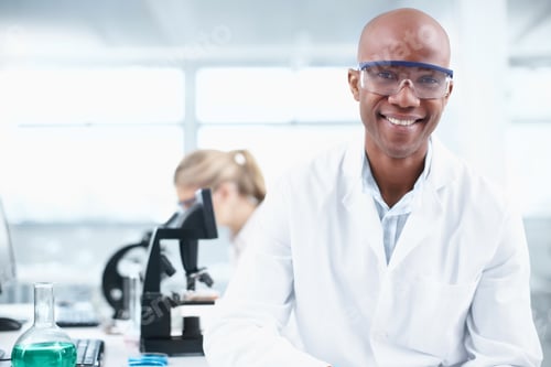 Preview: Portrait of a smiling young chemist in the lab with a female coworker in the background