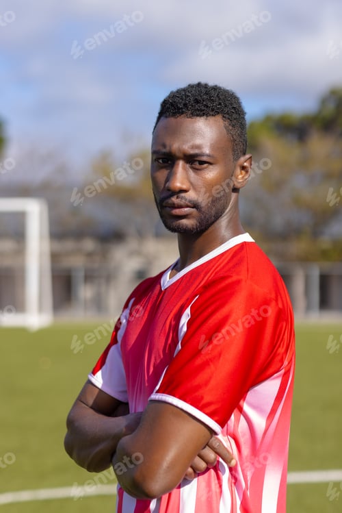 Preview: African American young male athlete standing on soccer field outdoors, looking serious, copy space