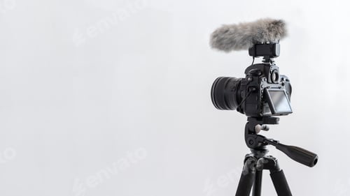 Black Camera with Microphone on Tripod on White