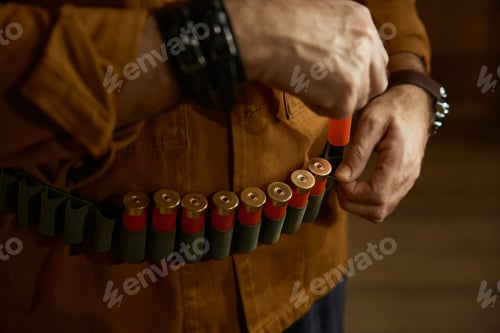 Preview: Closeup of hunter hands placing bullets into the ammo belt