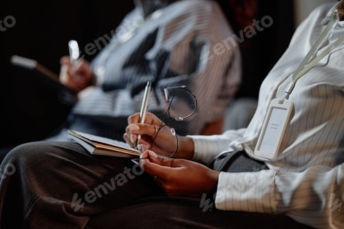 Preview: Black Businesswoman with Glasses Writing in Notebook during Business Meeting