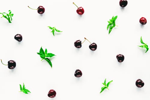 Preview: Dark red cherry and green mint leaves on white background, texture.