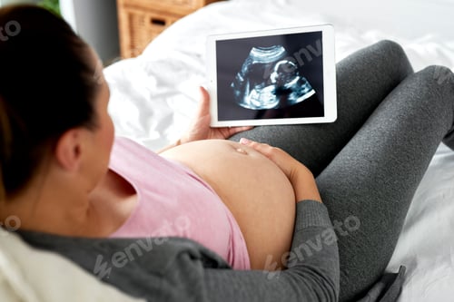 Preview: Pregnant woman watching at ultrasound record on tablet