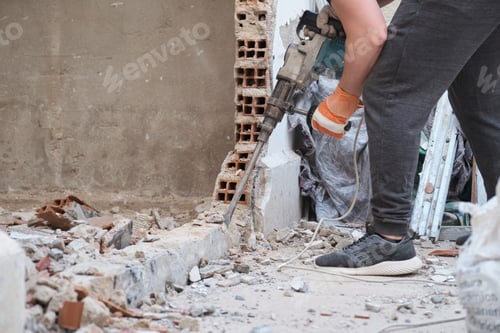 Preview: Unrecognizable man using a jackhammer to drill into wall.