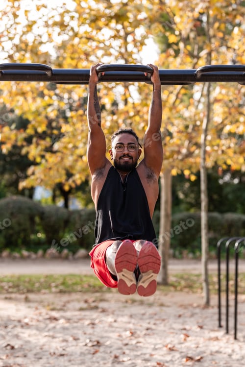 Preview: african american athlete boy does calisthenics fitness exercises on bars in park