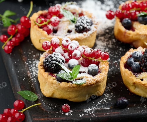 Preview: Fruit tart with red currants sprinkled with powdered sugar on a black table