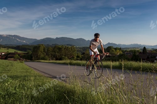 Preview: Young male cyclist cycling up rural road