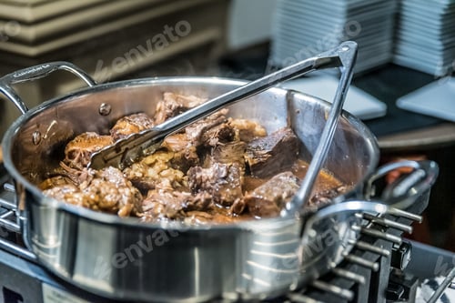 Preview: High angle shot of the delicious lamb pieces in a steel pot in a kitchen