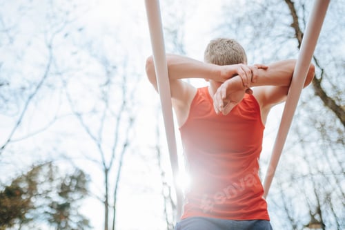 Preview: Tired sportsman taking a breather on parallel bars in the great outdoors